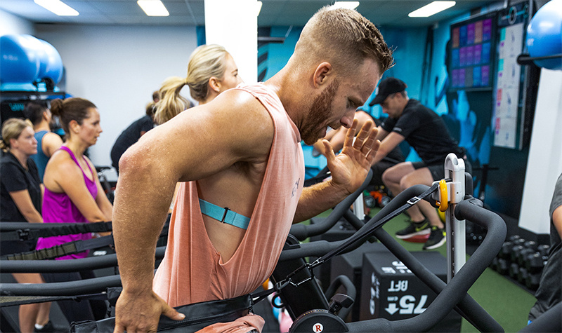 Body Fit Training studio workout attendee running on treadmill with heart monitor strapped to chest